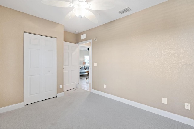 unfurnished bedroom featuring a closet, light carpet, and ceiling fan