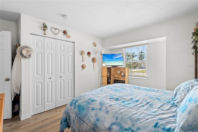 bedroom featuring a textured ceiling, light wood-type flooring, and a closet