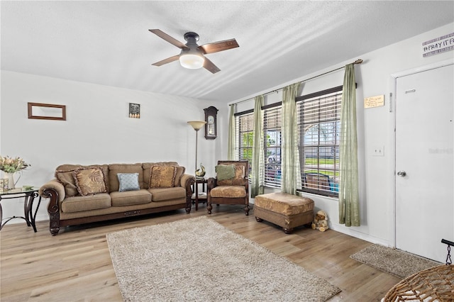 living room with a textured ceiling, light hardwood / wood-style flooring, and ceiling fan