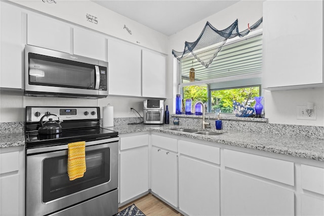 kitchen featuring white cabinetry, sink, light stone counters, and appliances with stainless steel finishes