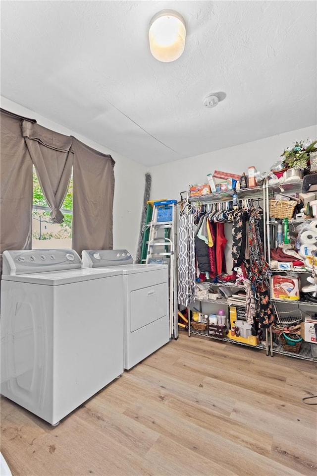 clothes washing area featuring independent washer and dryer and light hardwood / wood-style floors