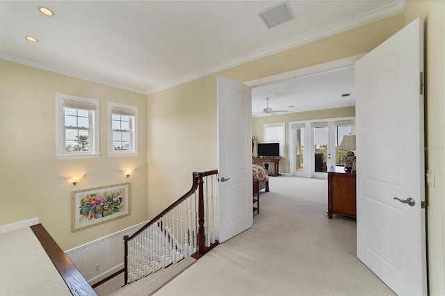 corridor with crown molding, french doors, light colored carpet, and a healthy amount of sunlight