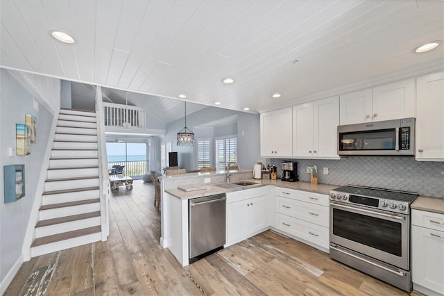 kitchen with sink, stainless steel appliances, pendant lighting, and white cabinetry