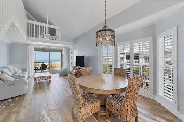 dining area featuring ceiling fan with notable chandelier, light hardwood / wood-style flooring, and high vaulted ceiling