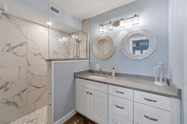 bathroom featuring wood-type flooring, vanity, and a tile shower