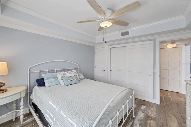 bedroom featuring crown molding, dark hardwood / wood-style flooring, ceiling fan, and a raised ceiling