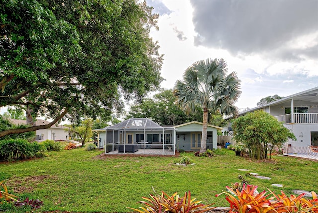 back of property featuring a lawn, glass enclosure, and a patio area