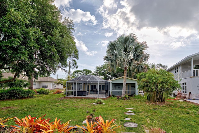 rear view of house with glass enclosure and a yard