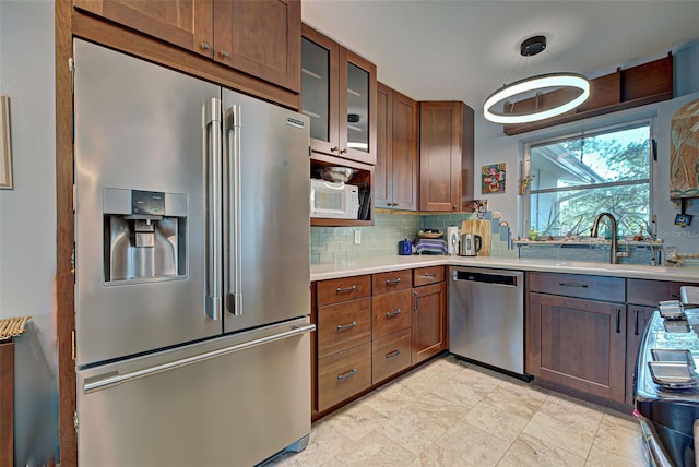 kitchen featuring backsplash, sink, decorative light fixtures, and appliances with stainless steel finishes