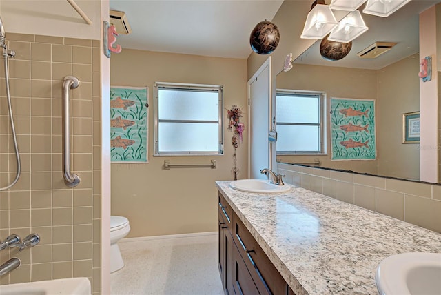 full bathroom with tiled shower / bath, vanity, and toilet