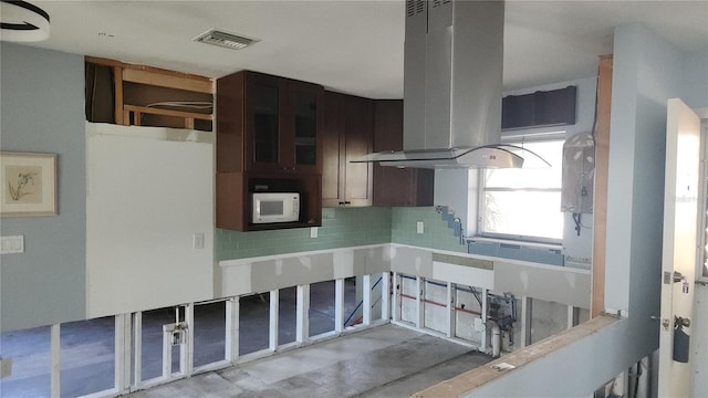 kitchen featuring dark brown cabinetry, island range hood, tasteful backsplash, and sink