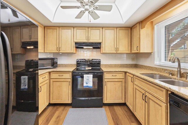 kitchen with black appliances, exhaust hood, ceiling fan, light wood-type flooring, and tasteful backsplash