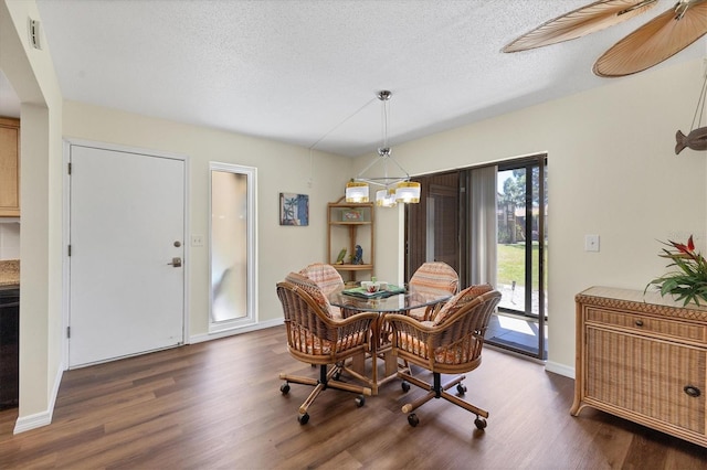 dining room featuring a textured ceiling, dark hardwood / wood-style flooring, and an inviting chandelier