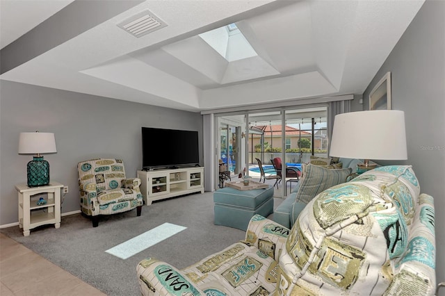 carpeted living room with a skylight and a tray ceiling