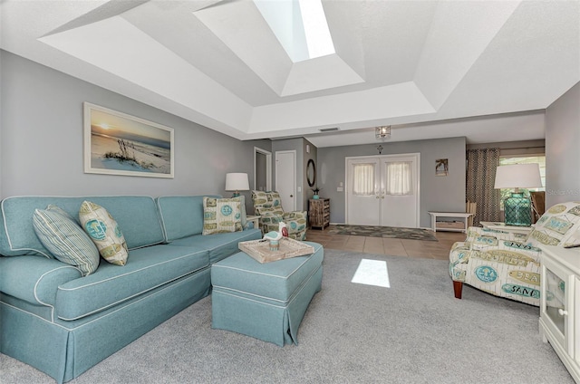 living room with a skylight, a tray ceiling, light tile floors, and a wealth of natural light