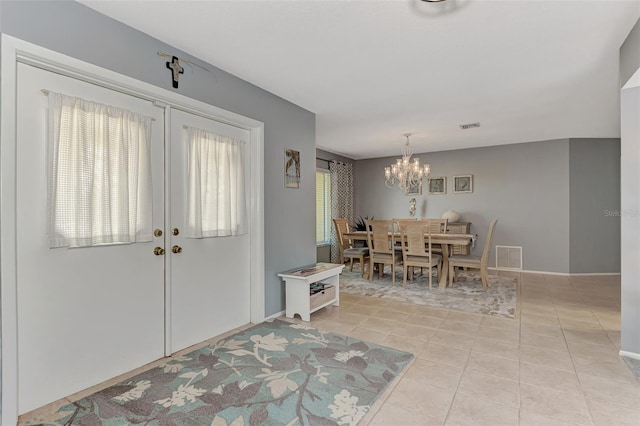 entrance foyer with an inviting chandelier, plenty of natural light, french doors, and light tile floors