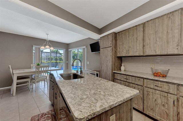 kitchen with hanging light fixtures, a kitchen island with sink, an inviting chandelier, sink, and tasteful backsplash