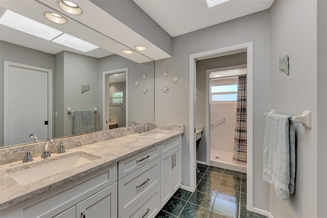 bathroom with a skylight, double sink, tile floors, and vanity with extensive cabinet space