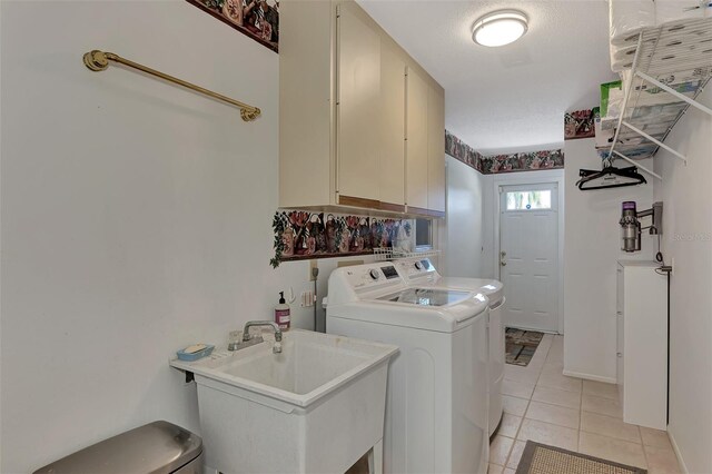 washroom with washing machine and clothes dryer, light tile floors, sink, electric dryer hookup, and cabinets