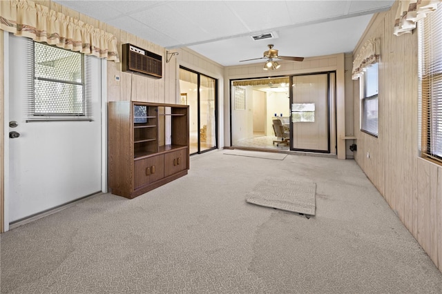 interior space featuring ceiling fan, an AC wall unit, light colored carpet, and wooden walls