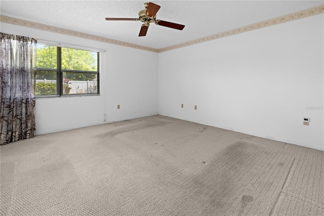 spare room with light colored carpet, a textured ceiling, and ceiling fan