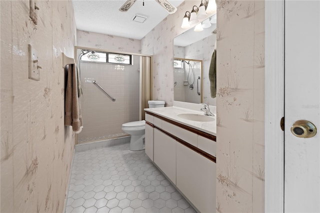 bathroom featuring toilet, tiled shower, vanity, a textured ceiling, and tile floors