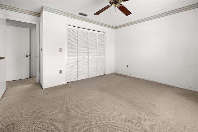 unfurnished bedroom with ceiling fan, crown molding, light colored carpet, and a closet