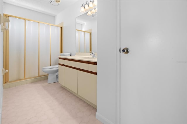 bathroom featuring vanity, toilet, a shower with shower door, and tile patterned flooring