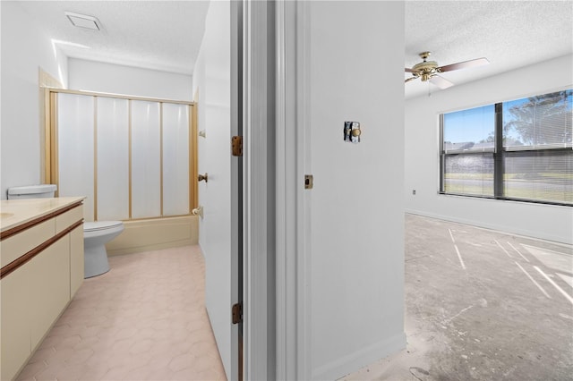 full bathroom with enclosed tub / shower combo, ceiling fan, vanity, a textured ceiling, and toilet