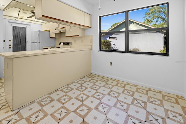 kitchen featuring stove, cream cabinets, light tile patterned flooring, decorative backsplash, and white fridge