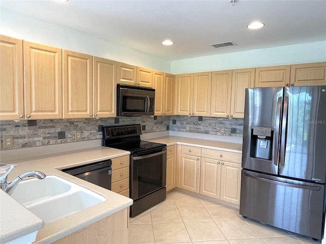 kitchen with sink, light tile patterned floors, light brown cabinets, appliances with stainless steel finishes, and decorative backsplash