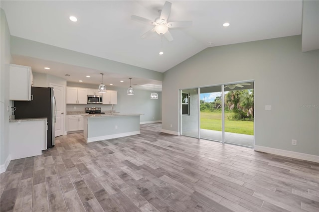 unfurnished living room with light hardwood / wood-style flooring, sink, ceiling fan, and vaulted ceiling