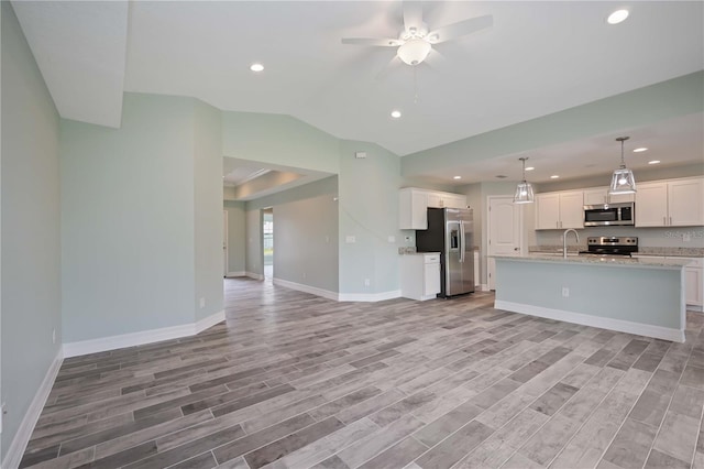 kitchen with white cabinetry, appliances with stainless steel finishes, light stone counters, light hardwood / wood-style floors, and ceiling fan