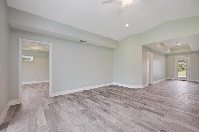 spare room with light hardwood / wood-style floors, ceiling fan, and a tray ceiling