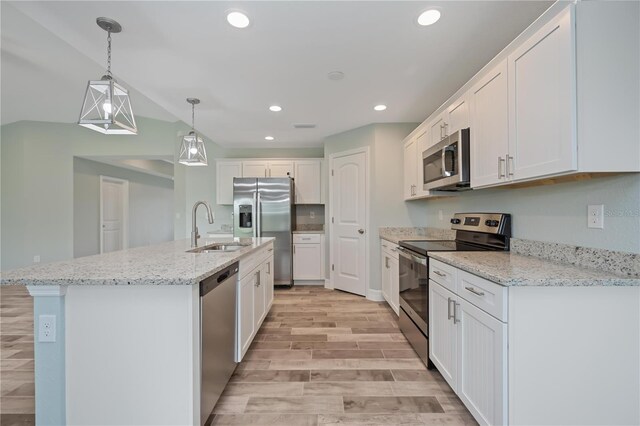 kitchen with appliances with stainless steel finishes, an island with sink, white cabinetry, sink, and pendant lighting