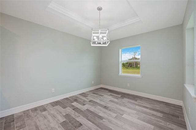 empty room featuring a chandelier, light hardwood / wood-style flooring, and a tray ceiling