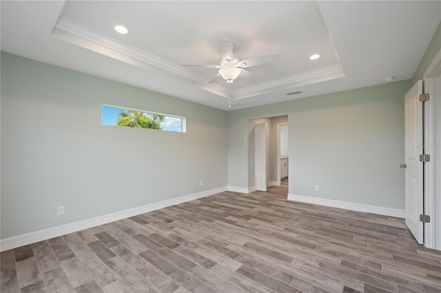 empty room featuring crown molding, light hardwood / wood-style floors, ceiling fan, and a tray ceiling