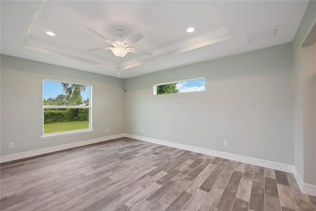 unfurnished room featuring ceiling fan, light hardwood / wood-style floors, and a tray ceiling