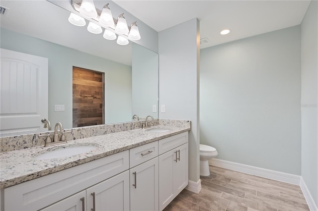 bathroom featuring hardwood / wood-style flooring, dual bowl vanity, and toilet