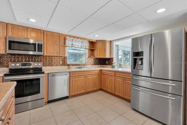 kitchen with backsplash, plenty of natural light, stainless steel appliances, and a drop ceiling