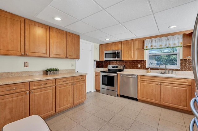 kitchen with light tile floors, appliances with stainless steel finishes, a paneled ceiling, and sink