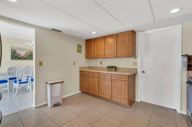 kitchen with electric range, a drop ceiling, an inviting chandelier, and light tile floors