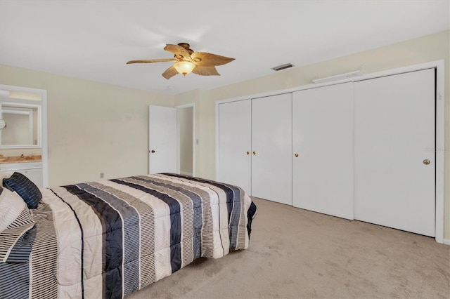 carpeted bedroom with ceiling fan and multiple closets