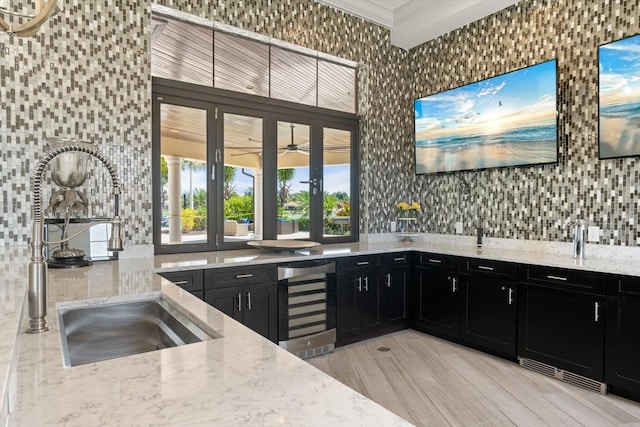 kitchen with light stone countertops, ceiling fan, crown molding, sink, and wine cooler