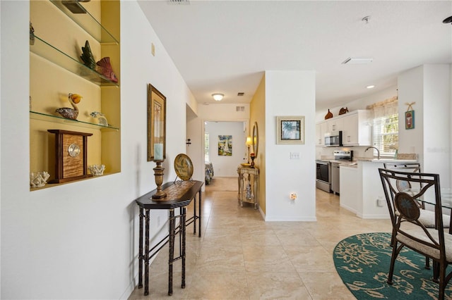 hall with sink and light tile floors