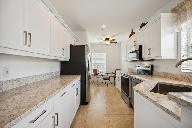 kitchen with a healthy amount of sunlight, ceiling fan, stainless steel appliances, and white cabinetry