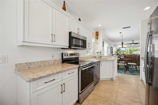 kitchen featuring decorative light fixtures, white cabinetry, black appliances, light tile floors, and light stone counters