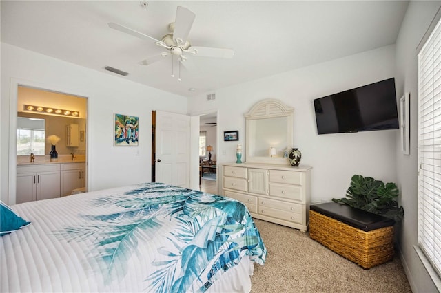 bedroom with ceiling fan, light carpet, and ensuite bathroom