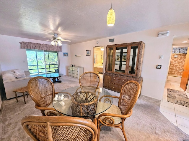 carpeted dining space with a textured ceiling and ceiling fan