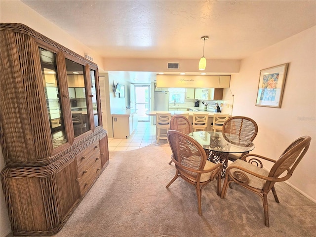 dining space with sink, a textured ceiling, and light carpet